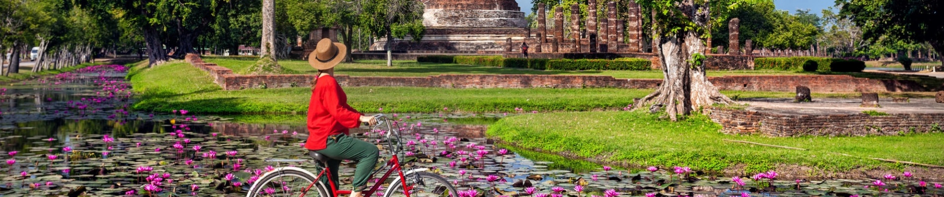 Femme à vélo devant un temple en Thaïlande